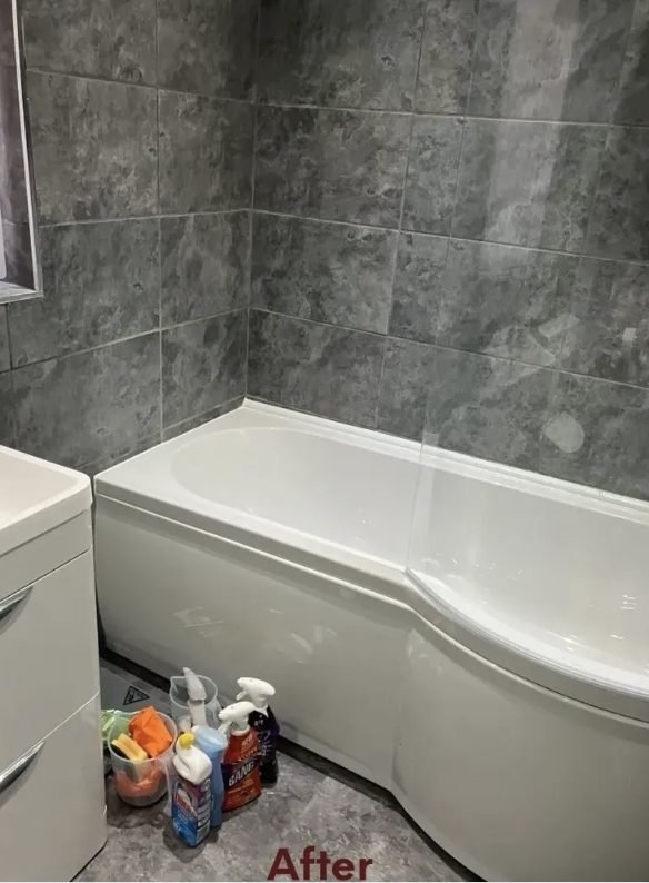 Newly fitted P-shaped bath with panel against grey tiling